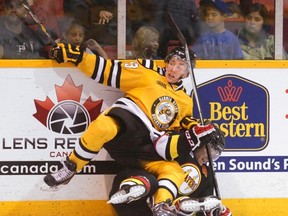 Sarnia Sting's Zachary Core checks Owen Sound Attack's Holden Cook into the side boards during first period OHL hockey action at the Lumley Bayshore on Wednesday  in Owen Sound. Jeff King scored the winner in a 3-2 overtime victory for Sarnia. (The Sun Times\JAMES MASTERS\QMI Agency).
