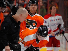 Brayden Schenn of the Philadelphia Flyers is helped off the ice by trainer Jim McCrossin after being hurt against the Washington Capitals at Wells Fargo Center on December 17, 2013. (Paul Bereswill/Getty Images/AFP)
