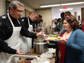 Acting Staff Sgt. Raymond Wood (left) and members of the Edmonton Police Service's School Resource Officer Unit help serve a Christmas meal at LY Cairns School, 10510 - 45 Ave., in Edmonton, Alta., on Thursday Dec. 19, 2013. David Bloom/Edmonton Sun