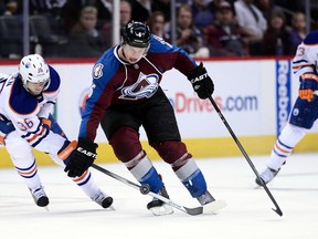 Oilers defenceman Philip Larsen battles Colorado's Erik Johnson for the puck during the second period Thursday in Denver. (USA TODAY)