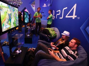 Visitors play a PlayStation 4 at the Sony exhibition stand during the Gamescom 2013 in Cologne Aug. 21, 2013. REUTERS/Ina Fassbender