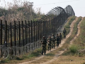 Indian Border Security Force soldiers patrol the fenced border with Pakistan at Babiya village, on Dec. 6. The border between the two countires remains a militarized hotspot after decades of disputes.
REUTERS/QMI AGENCY