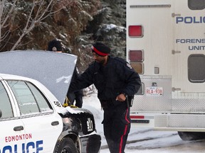 Two Edmonton Police Service officers work at a home on 76 Avenue near 79 Street in Edmonton, Alta., on Saturday, Dec. 21, 2013 after a report of two suspicious deaths. Ian Kucerak/Edmonton Sun/QMI Agency