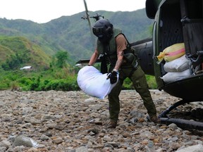 Master Corporal Stevenson Quinn, a 408 Tactical Helicopter Squadron flight engineer, unloads bags of food for the population of Barbaza, Antique Province, Philippines, on December 7, 2013 during Operation RENAISSANCE. Photo: Cpl Ariane Montambeault