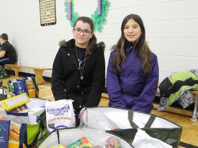 From left, Isabel de la Riva and Danica Paquette, both 13, with bags filled with groceries for needy families in the Ecole St-Joseph gym on Saturday. The Club Richelieu Les Patriotes will supply more than 100 families with the fixings for a delicious Christmas meal.  Laura Stricker/The Sudbury Star