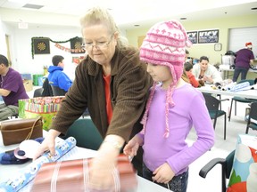 Suzanne Boyer and Caitlyn Jimmerskog, 7, helped wrap gifts to go to seniors with families at the ParkSide Centre on Saturday.  Laura Stricker/The Sudbury Star