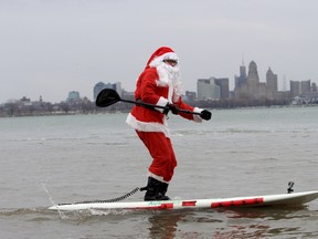 John Fulton, known as the Surfing Santa, rides a stand up paddleboard in Fort Erie Monday, Dec. 23, 2013. It was the 29th year the owner of Fulton Fitness has hit the water dressed as Santa. Dan Dakin, QMI Agency.