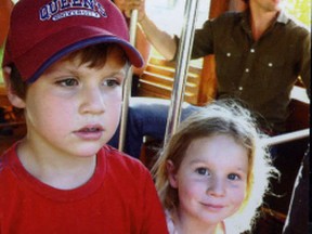 Donning a Queen's University ball cap Xavier Trudeau, the son of Liberal Party leader Justin, seen in background, takes the wheel of a bus, while his sister Ella Grace looks on. The image is used in the family's Christmas card this year.