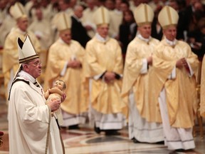 Pope Francis holds the baby Jesus statue at the end of the Christmas night mass in the Saint Peter's Basilica at the Vatican December 24, 2013. (REUTERS/Tony Gentile)