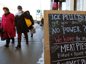 Christmas shoppers walk past a bakery advertising hot meat pies for residents whose electricity remains knocked out by an ice storm, on Danforth Avenue in Toronto December 24, 2013. (REUTERS/Chris Helgren)