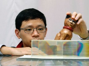 Nanyang Technological University (NTU) School of Physical and Mathematical Science researcher Zhang Baile shows how light passes through a set of carefully angled glass blocks to render an object invisible as he talks to the media about his research at NTU in Singapore Nov. 7, 2013.  REUTERS/Edgar Su