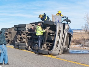 Pincher Creek Fire Chief Dave Cox speaks to crews working to rescue the driver from an overturned semi on Hwy. 22. High winds had blown over a total of seven trucks at that point. Greg Cowan photo/QMI Agency