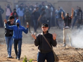 Al-Azhar University student supporters of the Muslim Brotherhood and deposed President Mohamed Morsi make the four-finger Rabaa gesture as they hold tear gas canisters during clashes with riot police and residents of the area at the Al-Azhar University campus in Cairo's Nasr City district December 28, 2013. One student was killed on Saturday and scores were arrested when supporters of the Muslim Brotherhood clashed with Egyptian police at the Cairo campus of Al-Azhar University, state media reported. The "Rabaa" or "four" gesture is in reference to the police clearing of the Rabaa al-Adawiya protest camp on August 14. REUTERS/Stringer