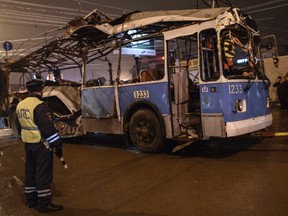 A policeman watches as a bus, destroyed in an earlier explosion, is towed away in Volgograd December 30, 2013.  (REUTERS/Sergei Karpov)