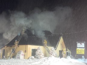 Smoke billows skyward while snow falls as firefighters battle a blaze at a Lucan restaurant Sunday night. (PATRICK MALONEY, The London Free Press)