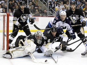 Jan 5, 2014; Pittsburgh, PA, USA; Pittsburgh Penguins goalie Marc-Andre Fleury (29) and defenseman Rob Scuderi (4) make a save on Winnipeg Jets center Bryan Little (18) during the third period at the CONSOL Energy Center. The Penguins won 6-5. Mandatory Credit: Charles LeClaire-USA TODAY Sports