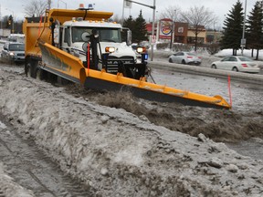 A city plow tries to push a pool of water off West Hunt Club near Merivale Rd. Monday morning as a soggy winter storm rolled through the city. That freezing rain and rain will re-freeze this afternoon when a cold front rolls in creating a flash freeze. (DOUG HEMPSTEAD Ottawa Sun)