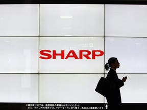 A woman walks past the Sharp Corp's Logo at a train station in Tokyo in this March 6, 2013 file photo.  REUTERS/Yuya Shino/Files