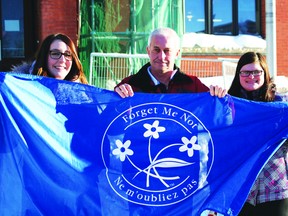 Mayor Dave Canfield (centre) joins Nikki Spencer (left) and Rylee Baird from the Kenora Alzheimer’s Society in raising a flag in recognition of Alzheimer’s Awareness Month on Jan. 2.