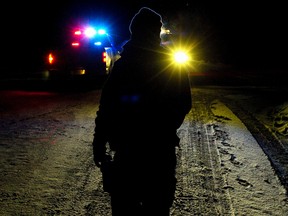An RCMP member mans a road block along Range Road 192 near Township Road 525, north of Tofield Alta., on Jan. 6, 2013. Two Mounties were injured in a violent encounter at a rural property nearby. RCMP confirmed one officer was shot and another was run over by a vehicle. David Bloom/Edmonton Sun/QMI Agency