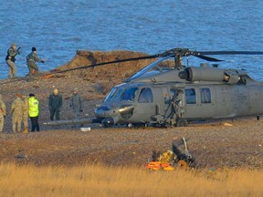 A Pave Hawk helicopter, military personnel and emergency services attend the scene of a helicopter crash on the coast near the village of Cley in Norfolk, eastern England on January 8, 2014. (REUTERS/Toby Melville)