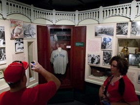 Visitors look at the jersey of baseball great Babe Ruth displayed in a Yankee Stadium locker at the National Baseball Hall of Fame in Cooperstown, New York. (REUTERS)