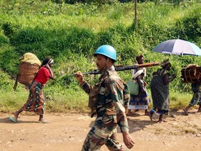 An Indian soldier, serving in the U.N. peacekeeping mission in Congo (MONUSCO), patrols past Congolese women walking to the market centre in Masisi, 88 km (55 miles) northwest of Goma Oct. 4, 2013. 
REUTERS/QMI Agency