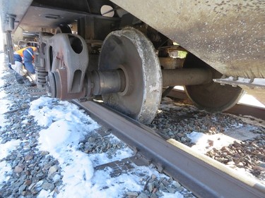 The Transportation Safety Board of Canada photo shows a investigator at the site of January 7, 2014 derailment involving Canadian National Railway (CN) mixed freight train, showing wheels which moved on the axle to the inside of the track and lost the track gauge, near Plaster Rock, New Brunswick in this handout image obtained on January 9, 2014. The New Brunswick train derailed in a rural area near a small village in eastern Canada. A total of 19 cars and one locomotive on the 122-car, four-locomotive train went off the rails. Three cars, one of them a crude tanker, were still burning on Thursday. REUTERS/The Transportation Safety Board of Canada/Handout via Reuters (CANADA - Tags: DISASTER TRANSPORT) ATTENTION EDITORS - THIS IMAGE WAS PROVIDED BY A THIRD PARTY. FOR EDITORIAL USE ONLY. NOT FOR SALE FOR MARKETING OR ADVERTISING CAMPAIGNS. THIS PICTURE IS DISTRIBUTED EXACTLY AS RECEIVED BY REUTERS, AS A SERVICE TO CLIENTS