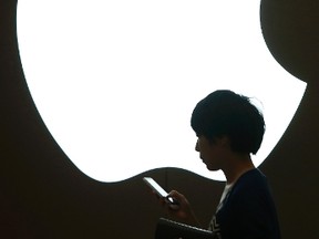 A woman looks at the screen of her mobile phone in front of an Apple logo outside its store in downtown Shanghai Sept. 10, 2013. REUTERS/Aly Song