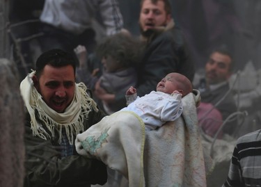 A man carries a baby who survived what activists say was an airstrike by forces loyal to Syrian President Bashar al-Assad in the Duma neighbourhood of Damascus January 7, 2014. REUTERS/Bassam Khabieh