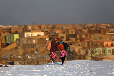 Afghan girls walk on snow as they head home in Kabul January 9, 2014. REUTERS/Mohammad Ismail