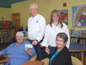 Mary Lou McMillan, seated left, supervisor of the John Kenneth Galbraith Reference Library in Dutton and Shelley Fleming, supervisor of the West Lorne library display cheques for $1,500 each from Mike Brady, back left and Laurie Reid of the Dutton and District Lions Club.