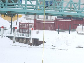 Steve Clark, a water resources technician with the St. Clair Conservation Authority, tests the strength of the ice on the Sydenham River on Friday, by throwing a 30-kilogram piece of metal off the Lou Stonehouse Bridge in Wallaceburg, Ont, onto the ice. (DAVID GOUGH, QMI Agency)