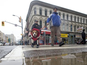 Pedestrians are reflected in a puddle on Richmond St. as a thaw begins (CRAIG GLOVER, The London Free Press)