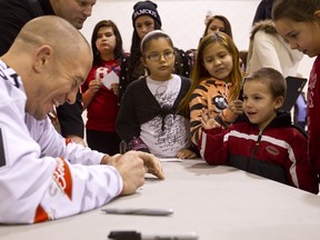 UFC fighter Georges St. Pierre signs an autograph with James Dion, 4, at the Crystal Kids Youth Centre in Edmonton Saturday. He was scheduled to appear at the Edmonton Rush game later. (IAN KUCERAK/Edmonton Sun)