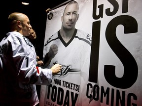 UFC fighter Georges St. Pierre signs a poster after the Edmonton Rush beat the Colorado Mammoth during the Rush's season home opener in Edmonton, Alta., on Saturday, Jan. 11, 2014. St. Pierre, attended the lacrosse team's game as a special guest. The team won 17-6. Ian Kucerak/Edmonton Sun/QMI Agency