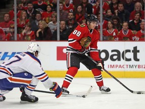 Patrick Kane #88 of the Chicago Blackhawks looks to pass under pressure from Boyd Gordon #27 of the Edmonton Oilers at the United Center on January 12, 2014 in Chicago, Illinois.   Jonathan Daniel/Getty Images/AFP