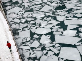 A jogger runs on a path beside the cracked ice in the Chicago River in Chicago, Ill., in this December 19, 2013 file photo. (REUTERS/Jim Young)