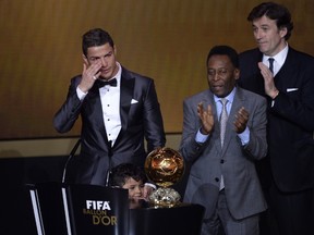 Brazilian football legend Pele (R) applauds next to Real Madrid's Portuguese forward Cristiano Ronaldo as he cries after receiving the 2013 FIFA Ballon d'Or award for player of the year during the FIFA Ballon d'Or award ceremony at the Kongresshaus in Zurich on January 13, 2014. (AFP PHOTO / FABRICE COFFRINI)