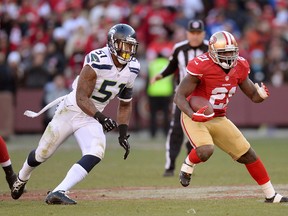 49er Frank Gore carries the ball, pursued by Seahawk Bruce Irvin December 8, 2013. (Thearon W. Henderson/Getty Images/AFP)