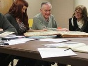 Members of the Byron Community Organization flip through a book of newspaper articles from the 1960s about West London during the groups latest meeting on Jan 9.