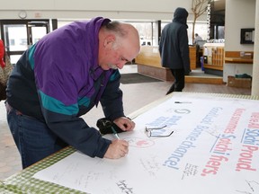 JOHN LAPPA/THE SUDBURY STAR
Raymond Chevrette signs an Olympic banner in support of local athletes at Tom Davies Square ion Wednesday. The banner is at city hall until Jan. 31. See video at www.thesudburystar.com.