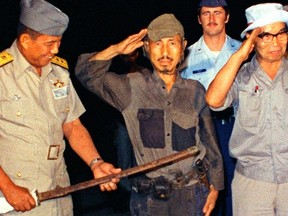 Hiroo Onoda, centre, salutes after handing over a military sword on Lubang Island in northwestern Phillippines, in this Kyodo file photo taken March 1974. (REUTERS/Kyodo/Files)