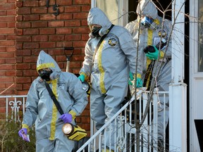 Investigators wearing protective suits leave a home on Lawson Rd. where containers of suspicious chemicals were discovered. (MORRIS LAMONT / THE LONDON FREE PRESS)