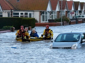 Emergency rescue service workers evacuate residents in an inflatable boat in flood water in a residential street in Rhyl, north Wales December 5, 2013. REUTERS/Phil Noble