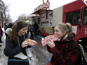 Anne Mienkowski, left, and Rebeccah Kennedy enjoy a Beavertail from a food truck park on the U of T campus on Jan. 17, 2014. (Craig Robertson/Toronto Sun)