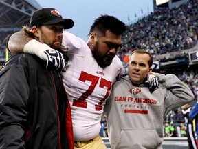 Guard Mike Iupati of the San Francisco 49ers is helped off the field in the second quarter while taking on the Seattle Seahawks during the 2014 NFC Championship at CenturyLink Field on January 19, 2014 in Seattle, Washington. (Christian Petersen/Getty Images/AFP)