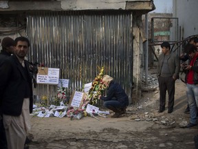 A journalist places flowers in tribute to the victims in front of the Lebanese restaurant which was attacked, in Kabul on January 19, 2014.  Survivors of the devastating Taliban suicide attack on a restaurant in Kabul told of the carnage and bloodshed, as details emerged of 21 people, including 13 foreigners, who died in the assault.  Desperate customers hid under tables when one attacker detonated his suicide vest at the fortified entrance to the Taverna du Liban and two other militants stormed inside and opened fire.  AFP PHOTO/JOHANNES EISELE