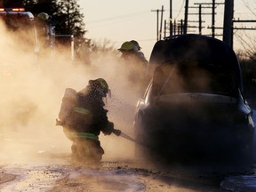 A firefighter works to put out hot spots in a car after it caught fire on Moira Street West in Quinte West Monday afternoon.
Emily Mountney/The Intelligencer/QMI Agency