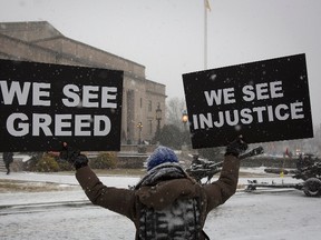 A woman holds up signs as she stands in quiet protest outside the War Memorial building in Trenton, New Jersey January 21, 2014. Governor Chris Christie is being sworn in today for his second term.     REUTERS/Carlo Allegri